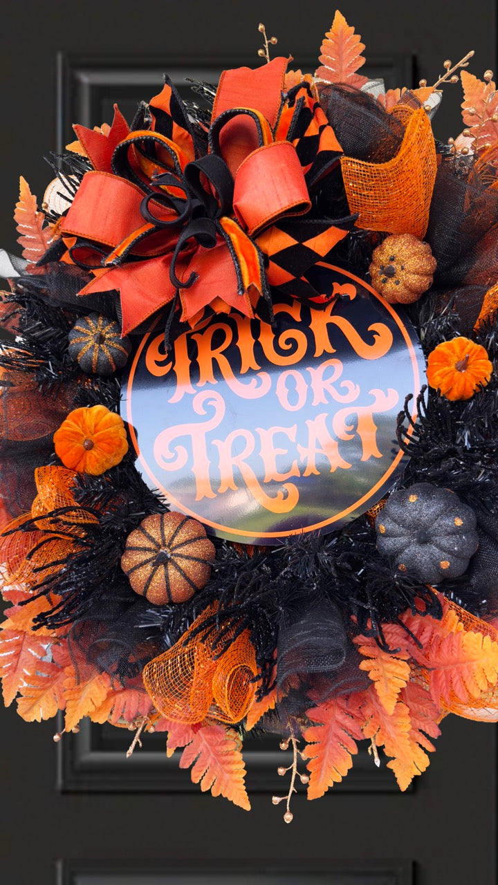 Black and orange Halloween wreath with layered mesh, designer ribbons, fall leaves, glitter pumpkins, and a round “Trick or Treat” sign.