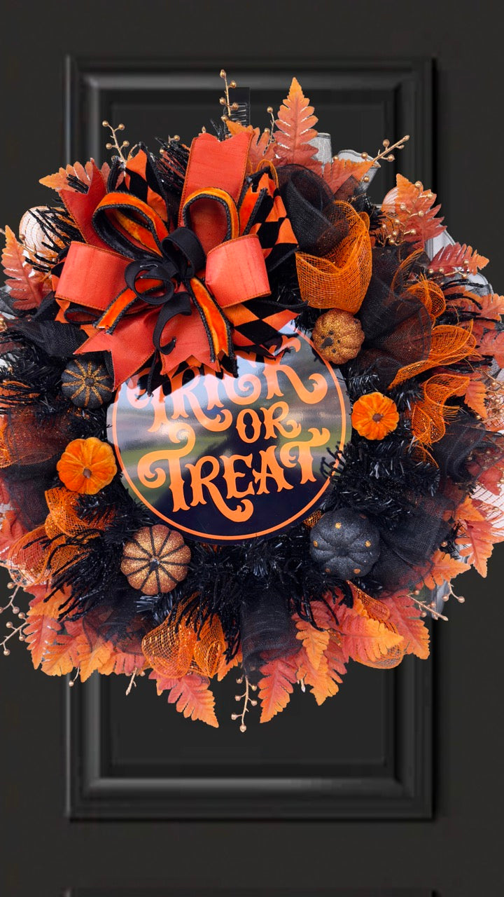 Black and orange Halloween wreath with layered mesh, designer ribbons, fall leaves, glitter pumpkins, and a round “Trick or Treat” sign.