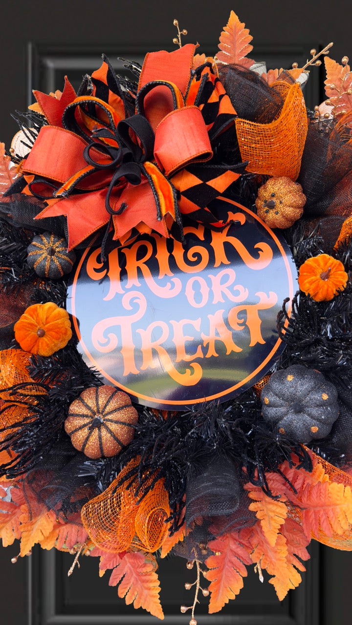 Black and orange Halloween wreath with layered mesh, designer ribbons, fall leaves, glitter pumpkins, and a round “Trick or Treat” sign.