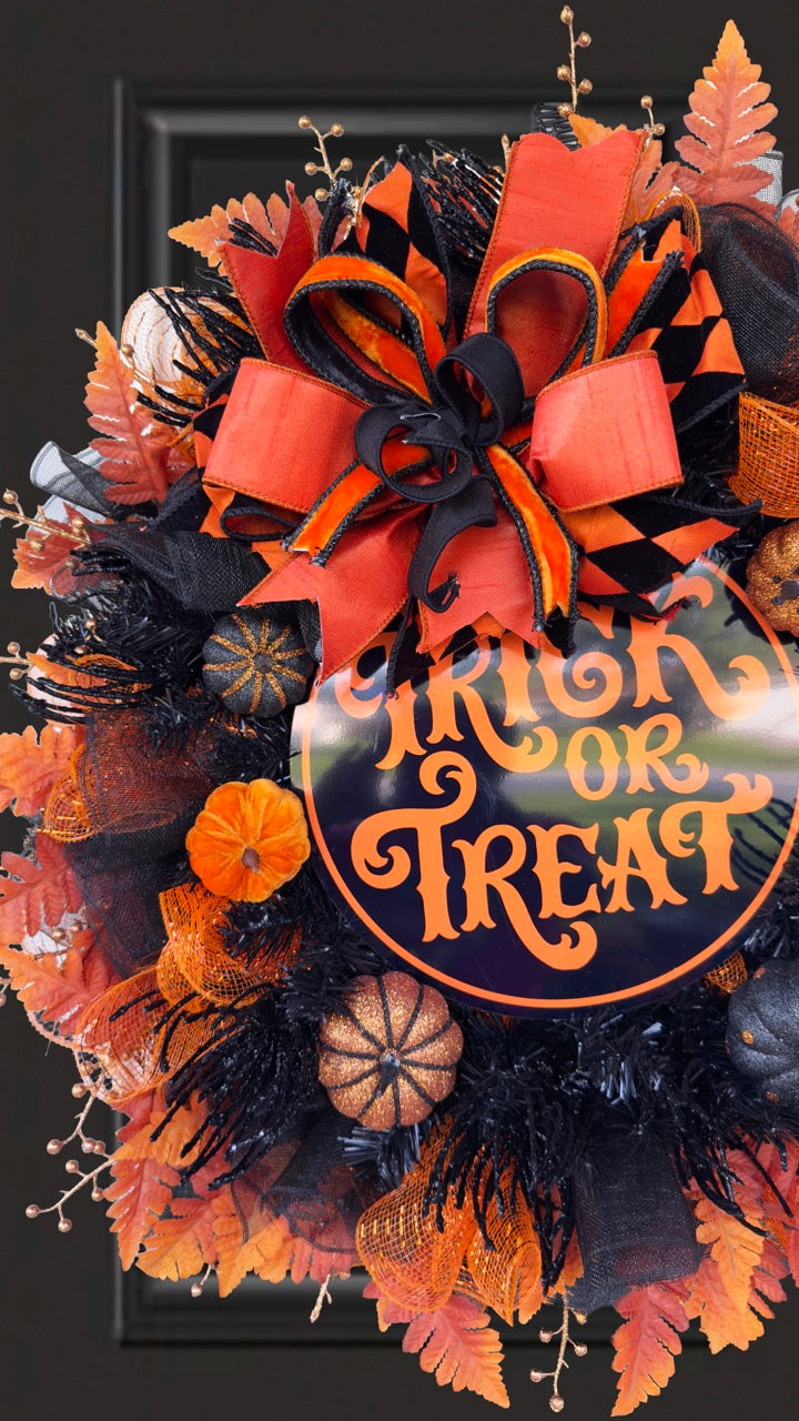 Black and orange Halloween wreath with layered mesh, designer ribbons, fall leaves, glitter pumpkins, and a round “Trick or Treat” sign.