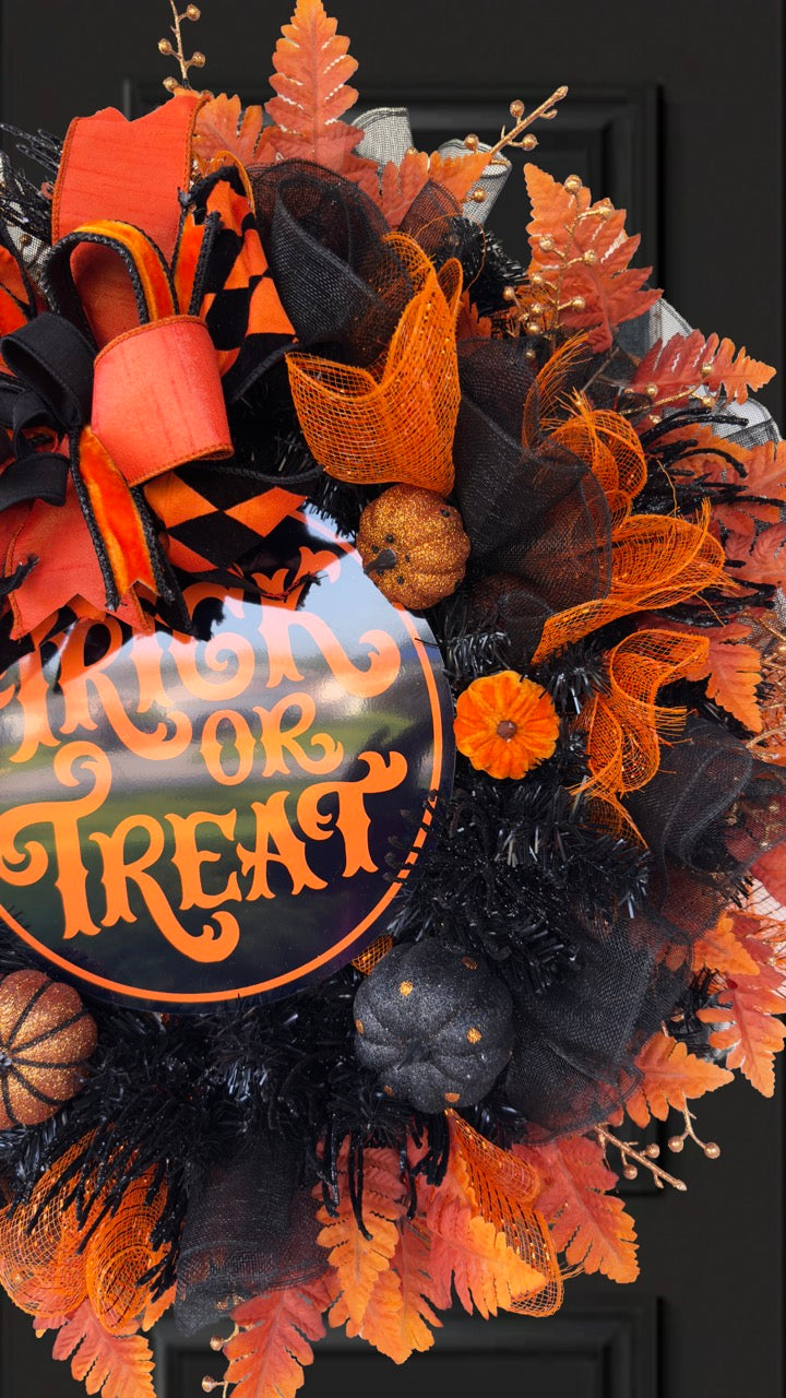 Black and orange Halloween wreath with layered mesh, designer ribbons, fall leaves, glitter pumpkins, and a round “Trick or Treat” sign.