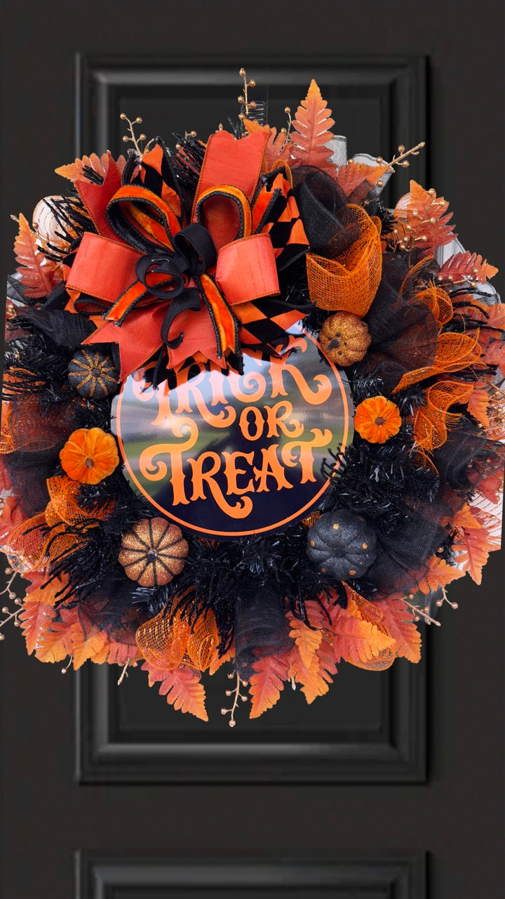 Black and orange Halloween wreath with layered mesh, designer ribbons, fall leaves, glitter pumpkins, and a round “Trick or Treat” sign.