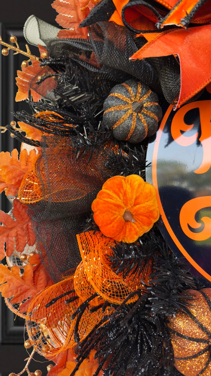 Black and orange Halloween wreath with layered mesh, designer ribbons, fall leaves, glitter pumpkins, and a round “Trick or Treat” sign.