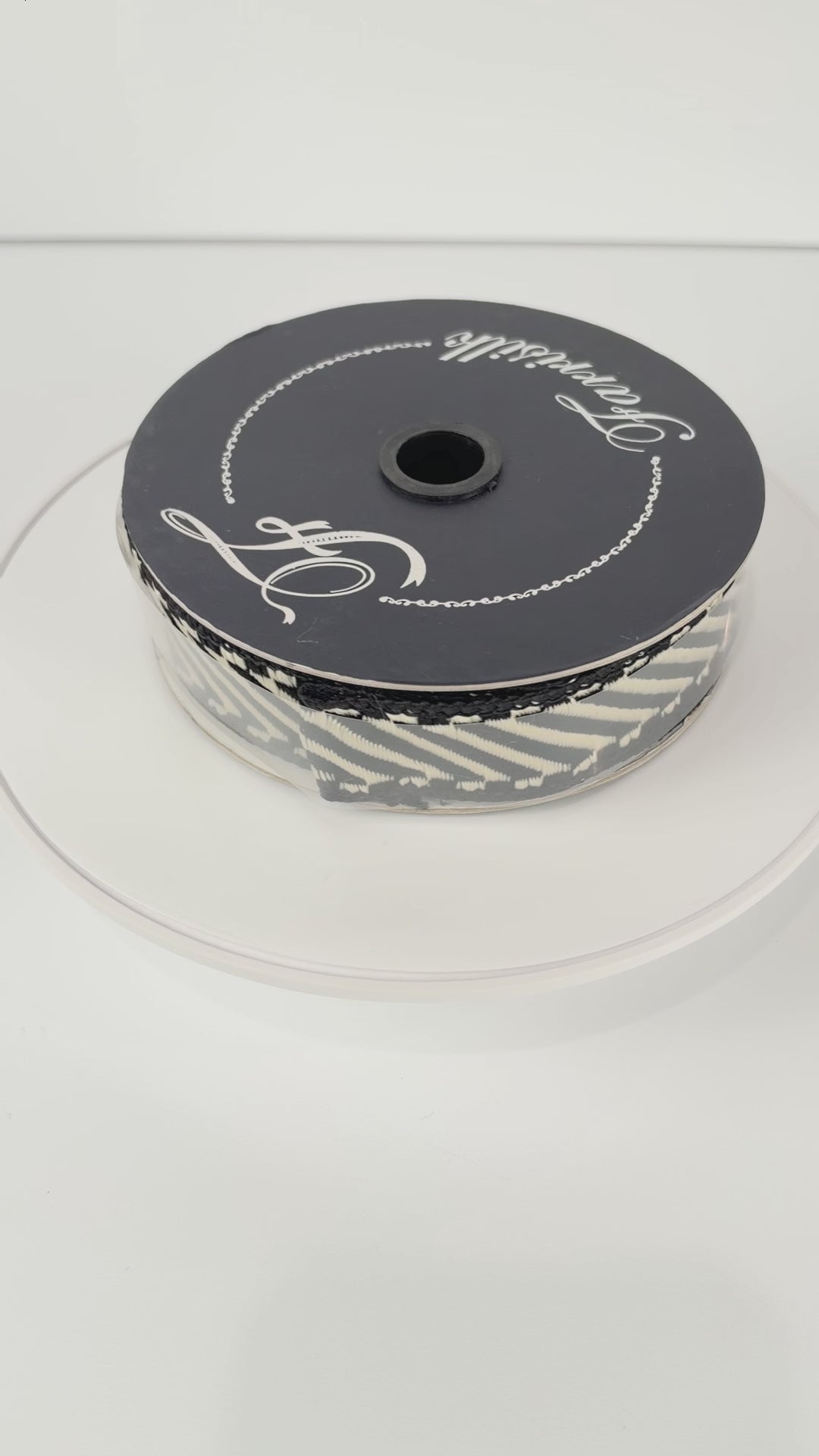Farrisilk Shapeshifter black and white geometric wired ribbon, 1 inches wide, displayed on a full 10-yard spool with decorative ribbon loops.