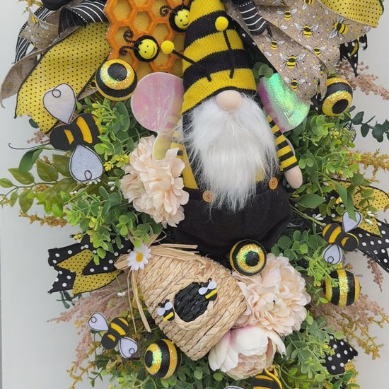 Handmade Queen Bee Manor wreath featuring a bee gnome, woven beehive, yellow and black designer bow, honeycomb accents, florals, bees, and lush greenery.
