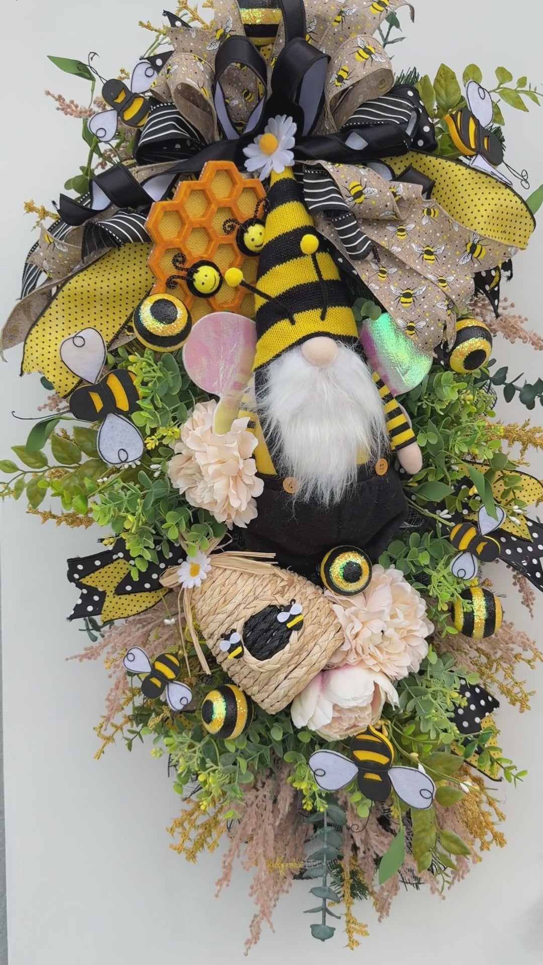Handmade Queen Bee Manor wreath featuring a bee gnome, woven beehive, yellow and black designer bow, honeycomb accents, florals, bees, and lush greenery.