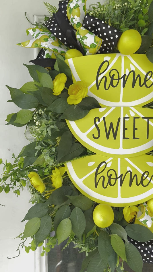 Handmade summer lemon wreath with stacked lemon slice signs reading ‘Home Sweet Home,’ decorated with yellow flowers, faux lemons, greenery, and polka‑dot and lemon‑print ribbons