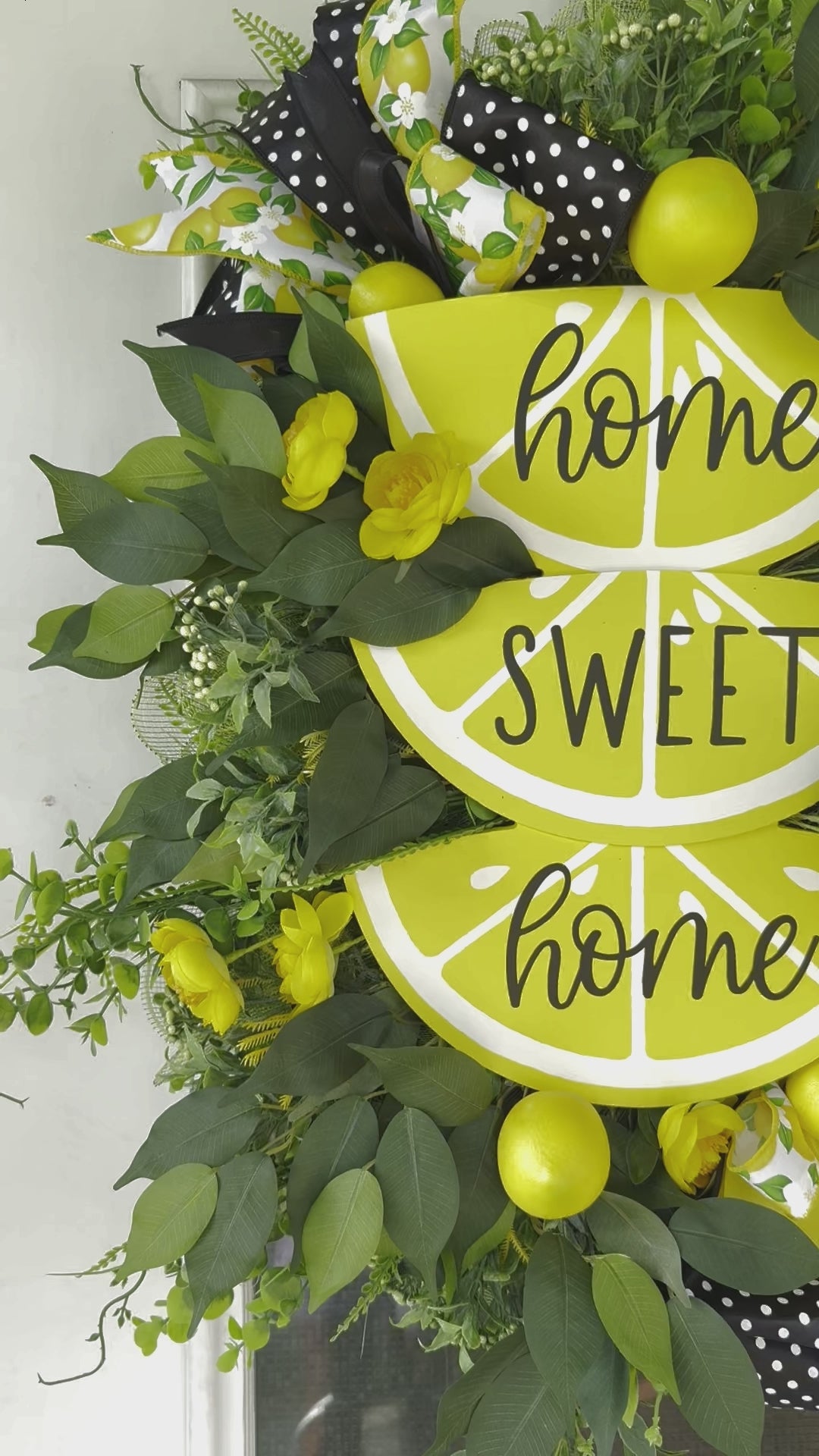 Handmade summer lemon wreath with stacked lemon slice signs reading ‘Home Sweet Home,’ decorated with yellow flowers, faux lemons, greenery, and polka‑dot and lemon‑print ribbons
