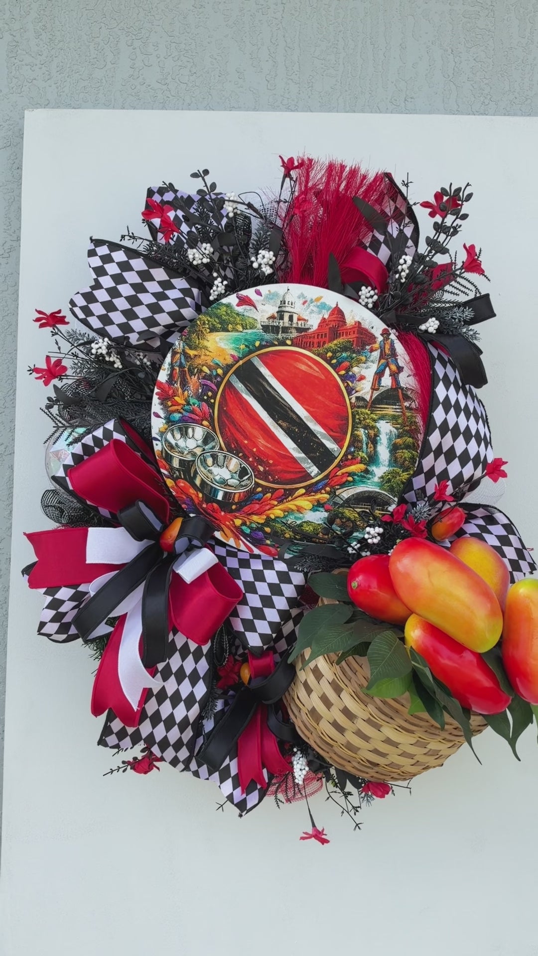 Handmade Trinidad and Tobago Caribbean front door wreath featuring a colorful Trinidad flag centerpiece, red black and white decorative bows, tropical greenery and woven basket filled with artificial peppers.
