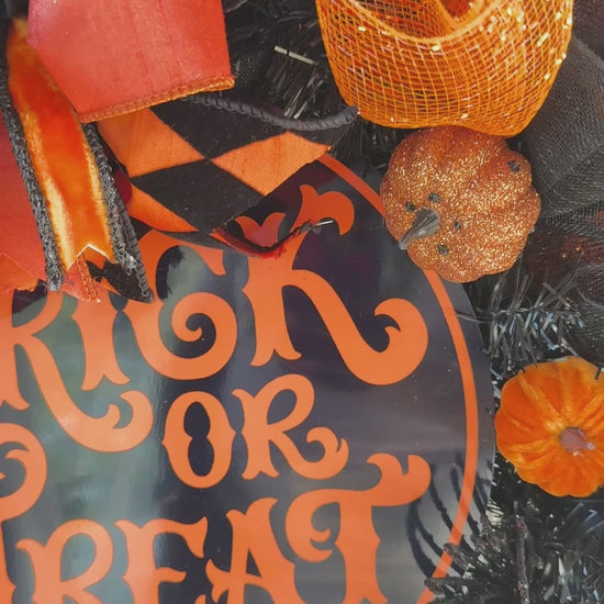 Black and orange Halloween wreath with layered mesh, designer ribbons, fall leaves, glitter pumpkins, and a round “Trick or Treat” sign.
