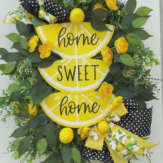 Handmade Lemon Sweet Home Summer Wreath featuring a yellow lemon-slice Home Sweet Home sign, bright yellow roses, decorative lemons, lush green foliage, and black-and-white polka-dot ribbon displayed on a white door.