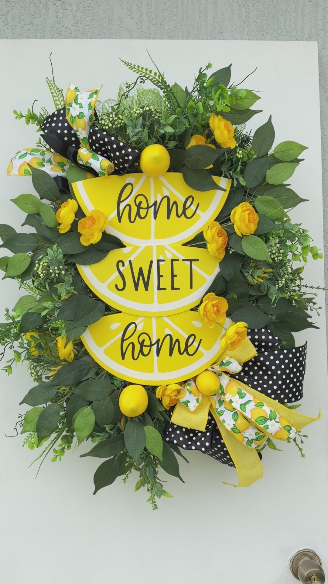 Handmade Lemon Sweet Home Summer Wreath featuring a yellow lemon-slice Home Sweet Home sign, bright yellow roses, decorative lemons, lush green foliage, and black-and-white polka-dot ribbon displayed on a white door.