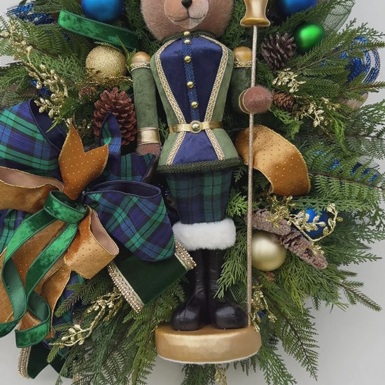 Full view of handmade teddy bear Christmas wreath with evergreen, navy ornaments and gold ribbon.
