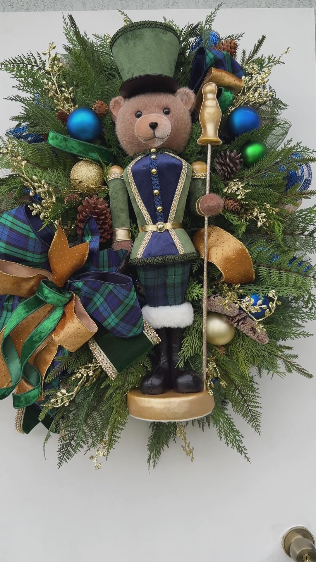 Full view of handmade teddy bear Christmas wreath with evergreen, navy ornaments and gold ribbon.